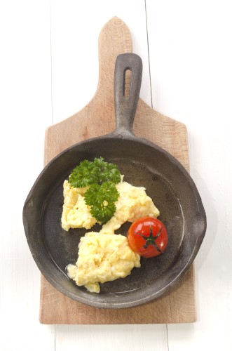 scrambled eggs, roasted tomato and parsley in an cast iron pan