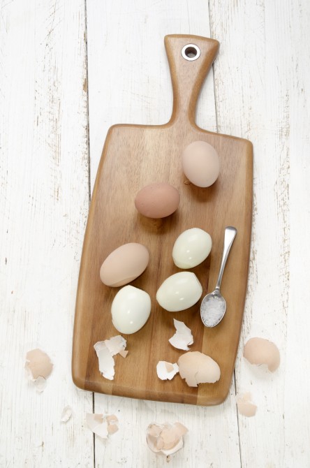 hard boiled eggs on a wooden board with spoon and coarse salt