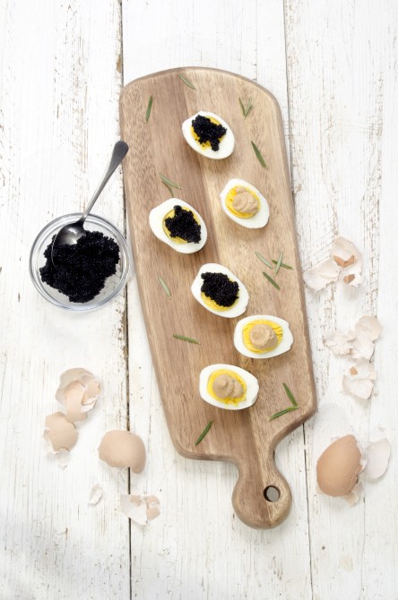 hard boiled eggs with caviar and salmon paste on a wooden board