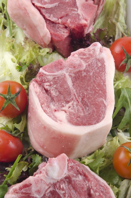 raw lamb chop with tomato and salad on a plate