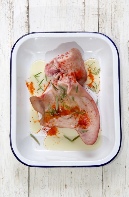 marinated pig ear with paprika and rosemary in a blue and white enamel bowl