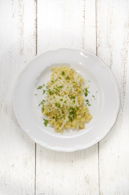 spaetzle with parsley, onion and melted cheese on a white plate