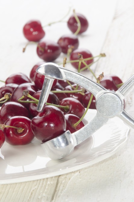 cherry stone remover and cherries on a plate