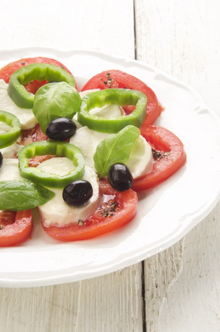 summer salad make from tomato, mozzarella, black olive, green chili and basil on a white plate summer salad make from tomato, mozzarella, black olive, green chili and basil on a white plate
