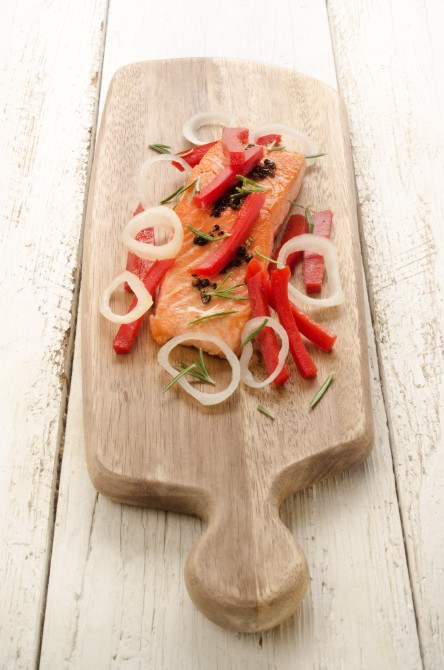 grilled salmon fillet with red paprika, onion rings and rosemary on wooden board