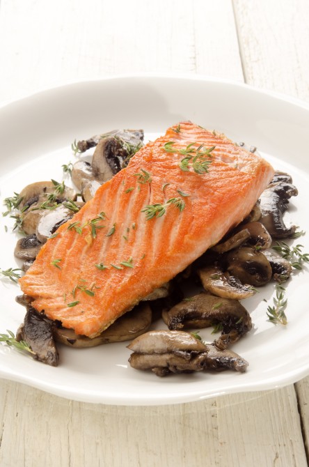 grilled salmon fillet with mushroom and thyme on a white plate