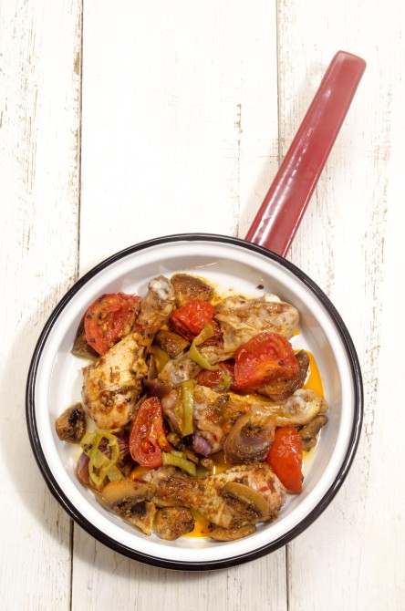 baked drumsticks with tomato, green paprika, lilac onion and mushroom in a red and white pan baked drumsticks with tomato, green paprika, lilac onion and mushroom in a red and white pan