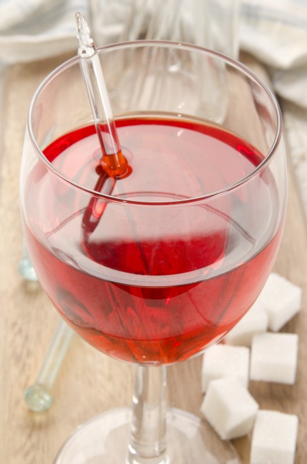 Red wine toddy in a glass with sugar cubes and glass pestle