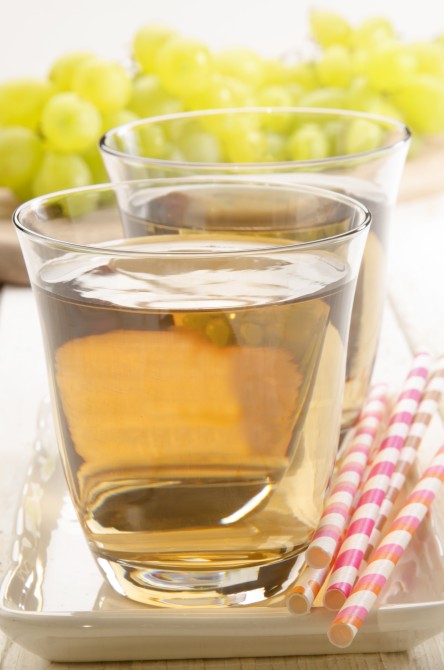 grape juice in a glass and grapes in the background