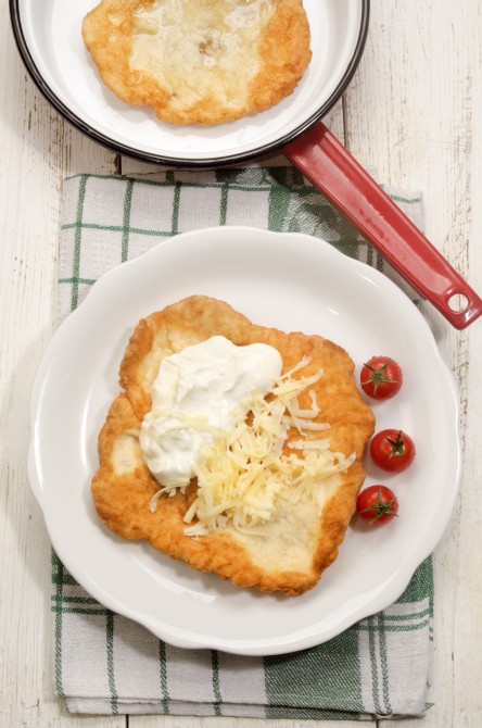 hungarian langos with sour cream, cheese and cherry tomato on a plate
