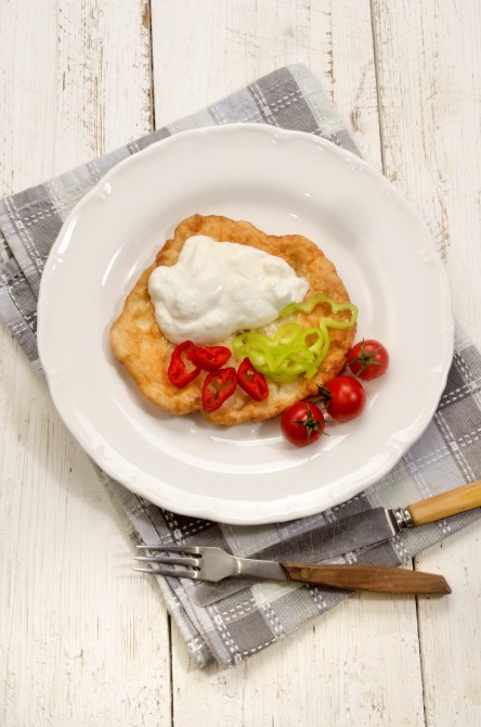 rustic hungarian breakfast with langos, sour cream and sliced chili on a plate rustic hungarian breakfast with langos, sour cream and sliced chili on a plate