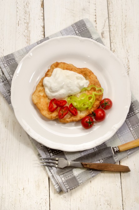 rustic hungarian breakfast with langos, sour cream and sliced chili on a plate 