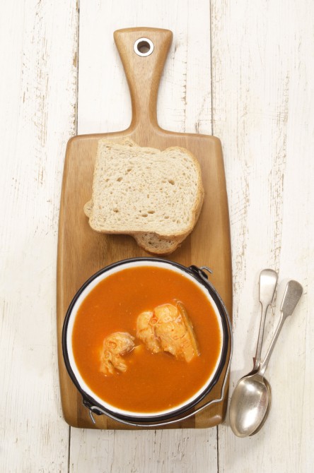 hungarian fish soup made from carp in a pot with bread on a wooden board