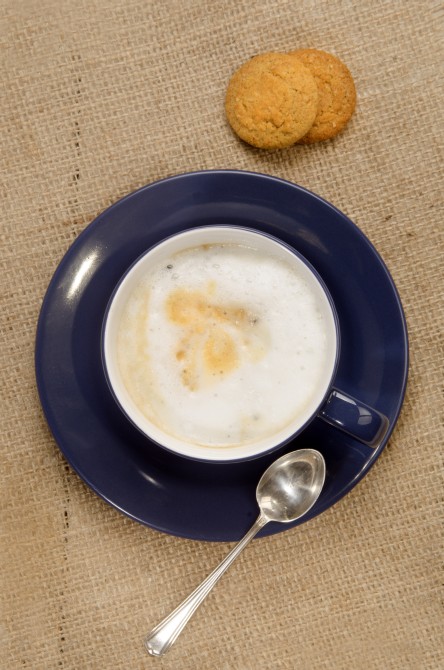 coffee with milk foam and biscuit on jute
