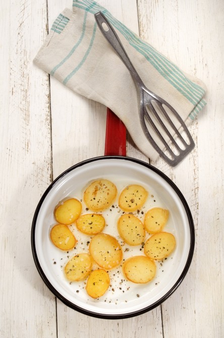 fried potato slice with crushed pepper and coarse salt in a pan