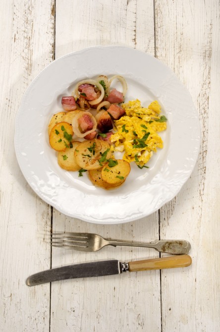 fried potato, bacon, scrambled eggs and parsley on a plate