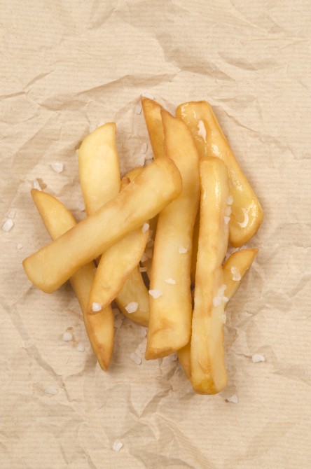 french fries with coarse salt on brown paper 