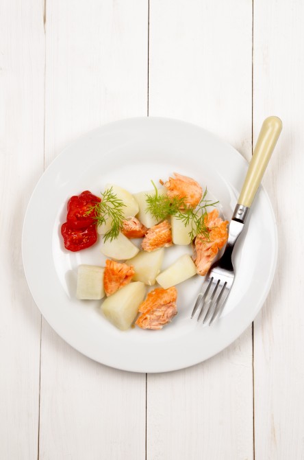 boiled potatoes with fried salmon, tomatoes and dill on a white plate