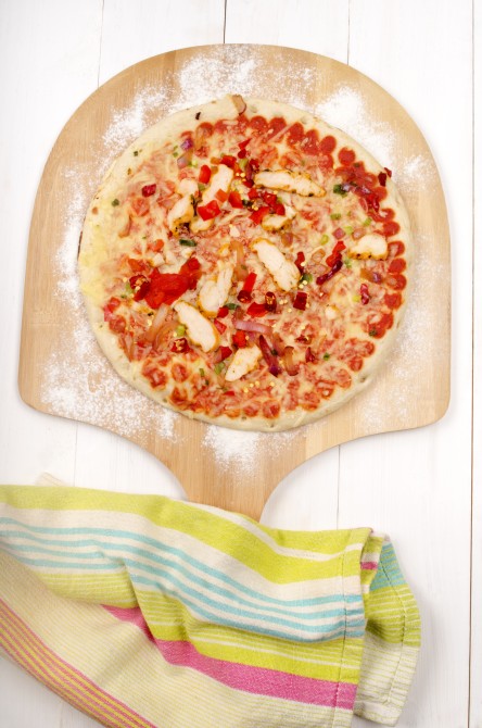 floury wooden board with a chicken, red onion and hot chilli stone baked pizza floury wooden board with a chicken, red onion and hot chilli stone baked pizza