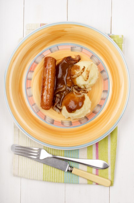 mashed potato with gravy, roasted onion rings and sausage on a plate