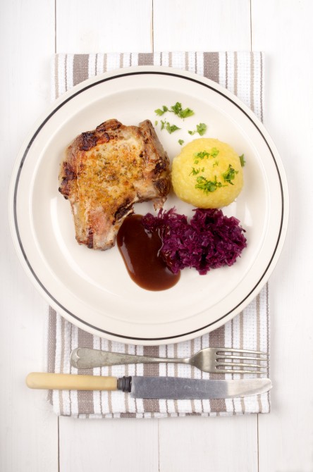pork chop with red cabbage, gravy and potato dumpling on a plate