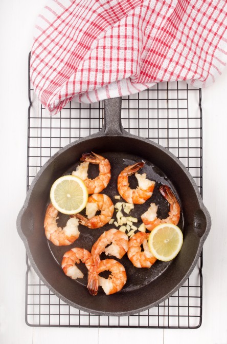 grilled king prawns with lemon slice and crushed garlic in a cast iron pan grilled king prawns with lemon slice and crushed garlic in a cast iron pan
