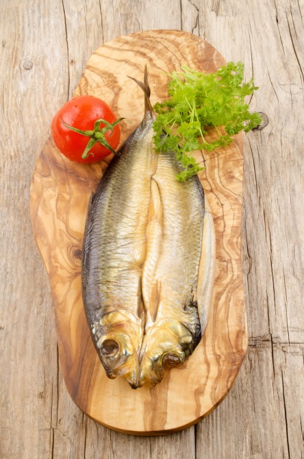 kipper with fresh tomato and parsley on wooden board kipper with fresh tomato and parsley on wooden board