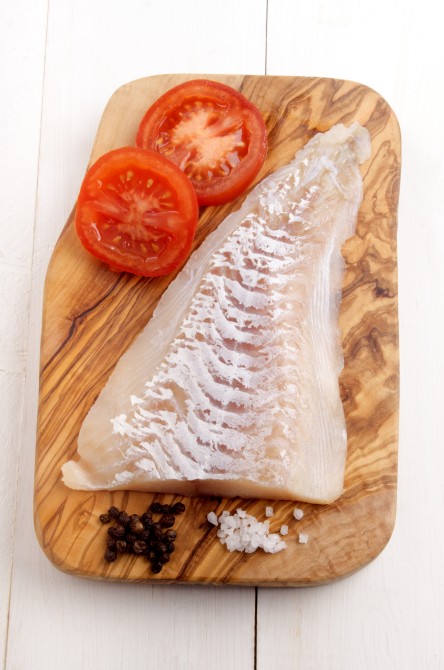 haddock fillet with tomato, pepper and coarse salt on a wooden board haddock fillet with tomato, pepper and coarse salt on a wooden board