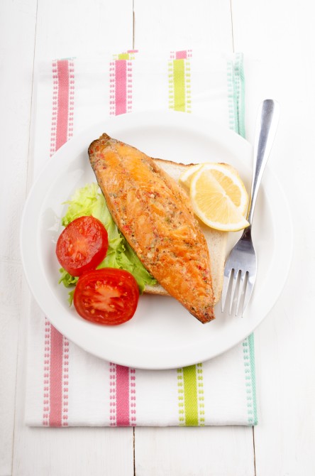 toast bread with smoked mackerel, tomato, salad and lemon on a plate