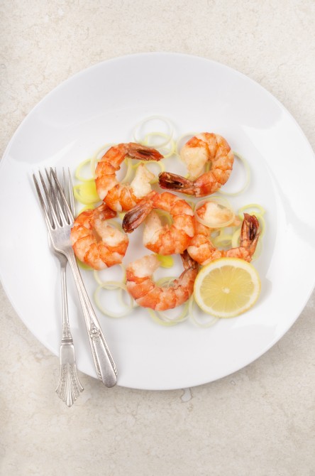 king prawn with slice lemon and cooked leek on a plate