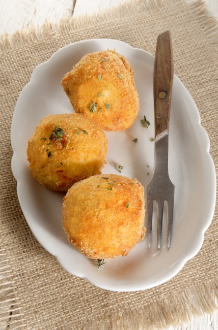 breaded potato balls with thyme and fork in a bowl