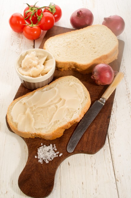 slice of bread with lard, tomatoes, purple onions and coarse salt on wooden board