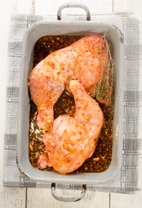 raw chicken leg with a home made marinade and thyme