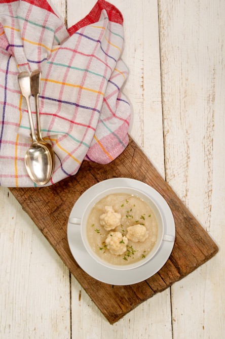 cauliflower soup with thyme in a bowl on rustic brown wood