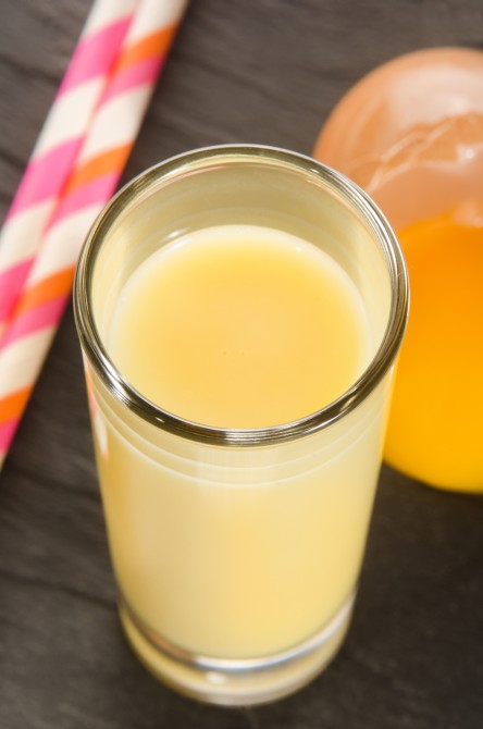 eggnog in a glass with straw and egg yolk on slate eggnog in a glass with straw and egg yolk on slate