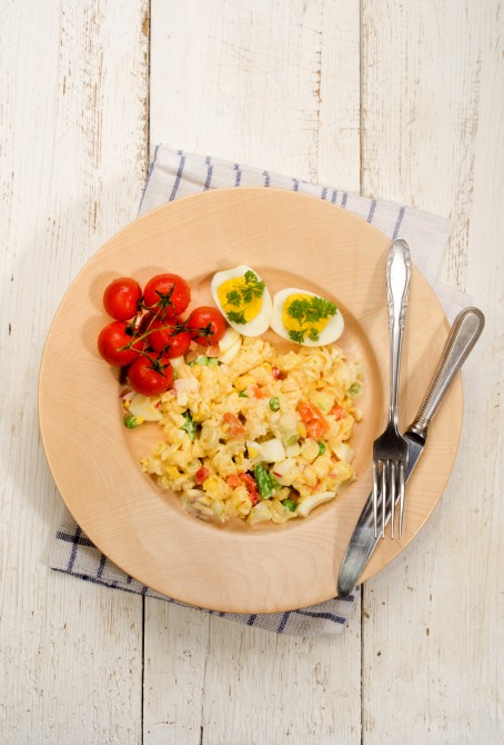 mixed vegetarian pasta salad with egg and vegetables on a wooden plate