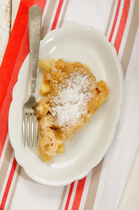 apple crumble with powdered sugar on oval plate and fork