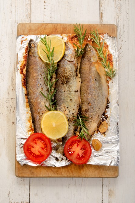 baked trout with lemon, garlic, rosemary, pepper, salt and sliced tomato