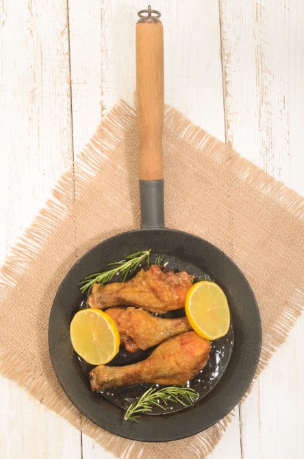honey glazed chicken drumsticks with slice lemon and rosemary in a pan