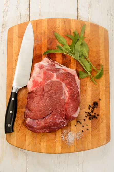 raw beef shoulder on wooden board with sage, salt and peppercorn raw beef shoulder on wooden board with sage, salt and peppercorn