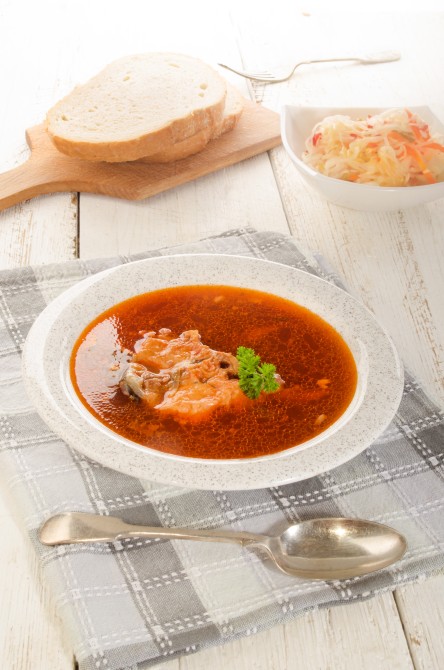 hungarian fish soup in a soup plate, salad and bread on a wooden board