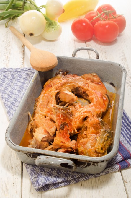 boiled carp in a rustic gray metal cooking tin, white onion and tomato boiled carp in a rustic gray metal cooking tin, white onion and tomato