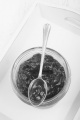 glass with plum jam and a small spoon on a white serving tray