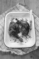 honey glazed chicken leg with olive oil, rosemary, meat fork in an blue and white enamel rosting dish