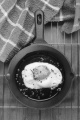 fried egg with crushed pepper and coarse salt in a cast iron pan on cooling rack