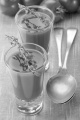 tomato soup as appetizer in a shot glass with thyme on green table cloth