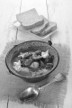 authentic hungarian goulash in a kettle with bell pepper, potato, carrot, sour cream and bread on a plate
