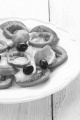 summer salad make from tomato, mozzarella, black olive, green chili and basil on a white plate
