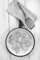 fried potato slice with crushed pepper and coarse salt in a pan