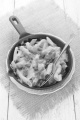 pasta with grilled bacon, thyme and melted cheese in a cast iron pan